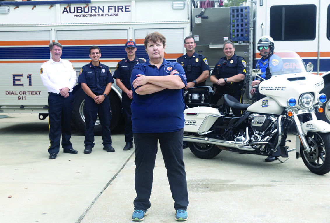 JoEllen Sefton standing in front of members of the Auburn Police and Fire Departments.