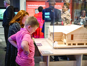 Two students looking at a display of a model home