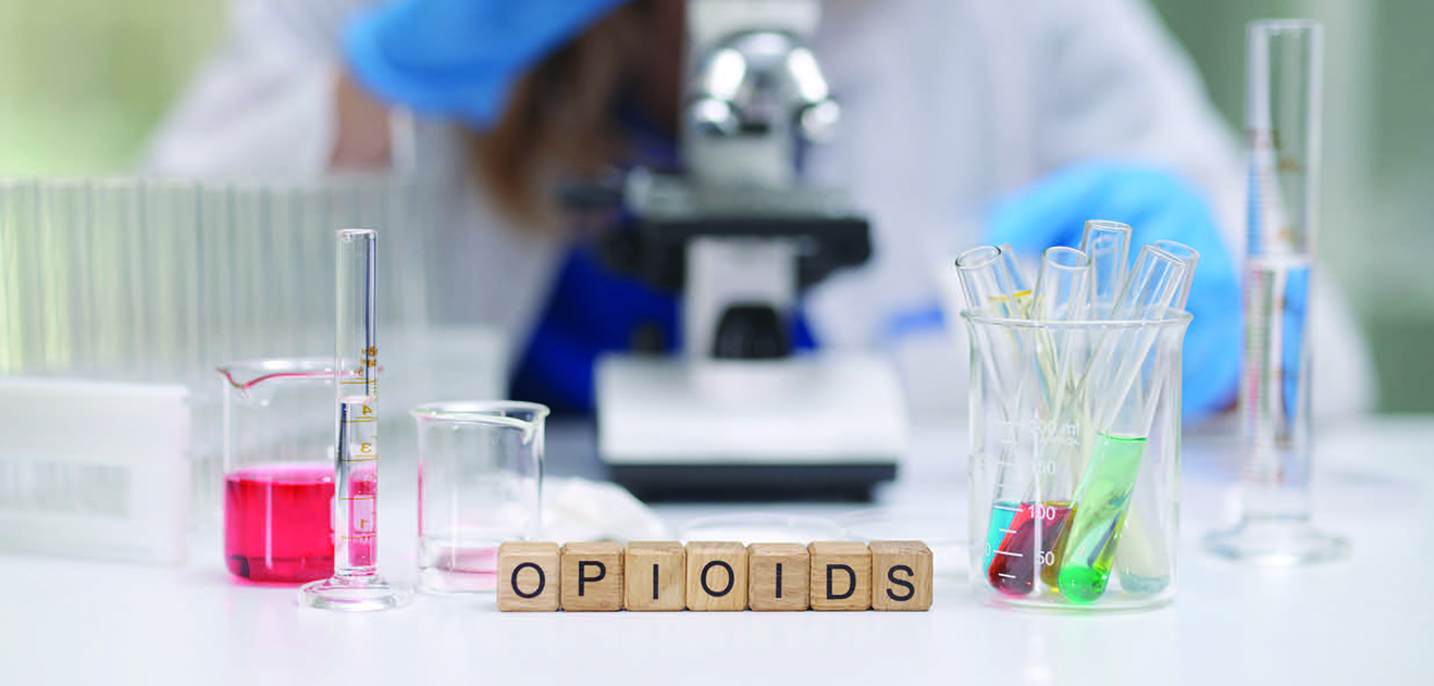 Image of beakers and flasks with the work OPIOIDS spelled out with blocks.