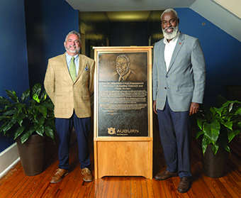 Sean Forbes, recognized for his outstanding community work through Opelika Grows (O Grows), proudly receives the prestigious Royrickers Cook Endowed Engagement Award. Pictured with Vice President Royrickers Cook, Forbes stands beside the bronze plaque that now bears his name. O Grows exemplifies Auburn’s pillars of research, instruction, and outreach. It features a year-round community garden, a state-certified farmers market, youth and adult educational programs, and demonstration workshops.