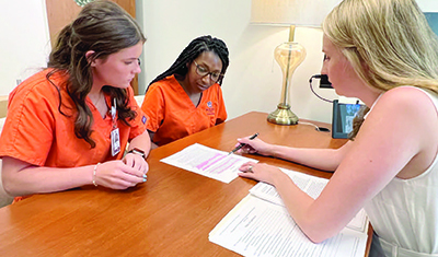 Kendall Henderson and two nursing students sit at a desk.