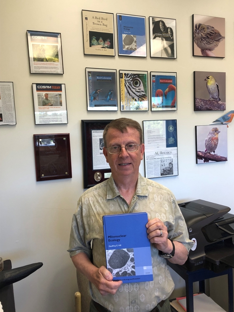 Dr. Hill standing in front of his previously released books.