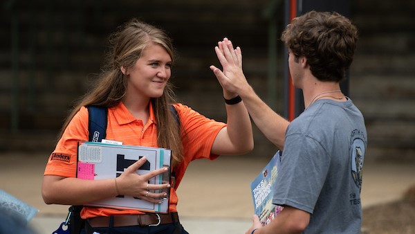 A Camp War Eagle Counselor giving a student a high five.