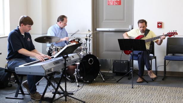 Members of OIT playing keyboard, drums, and bass guitar.