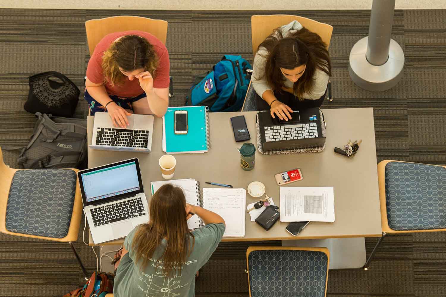 Students using laptops at a table on campus