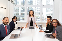 Five people around a conference table using laptops.