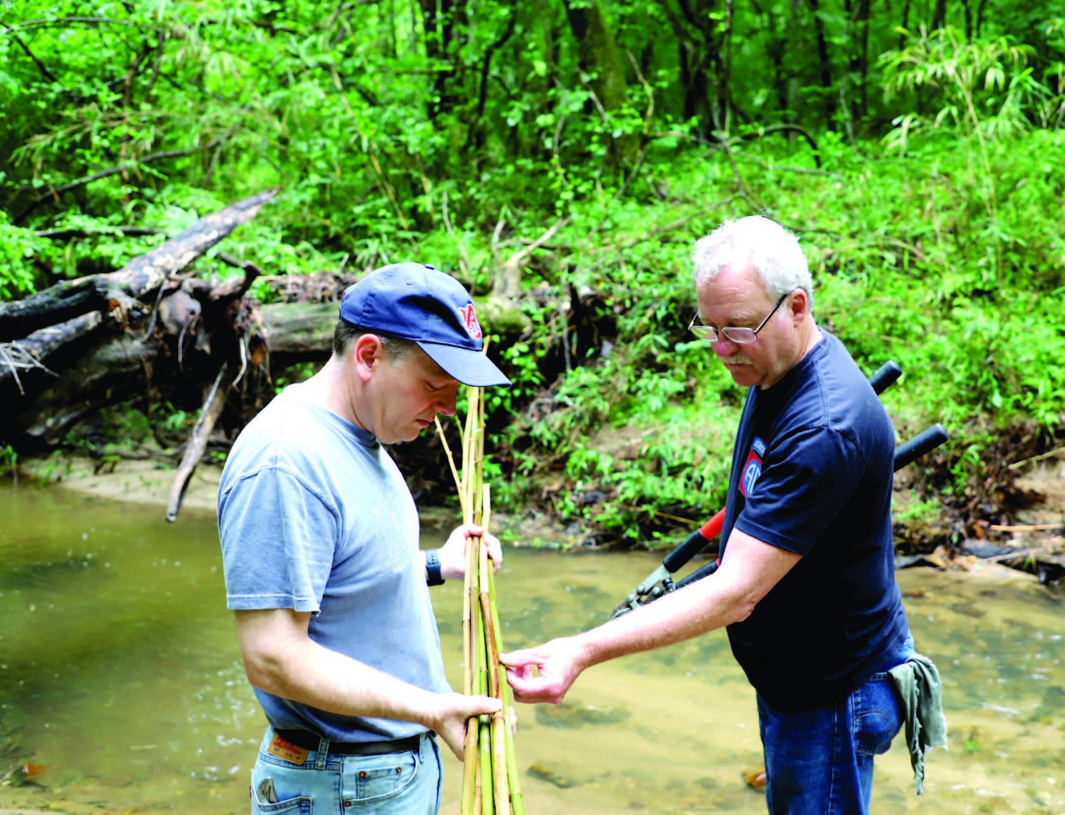 Basket weaver Robert Haygens and Center Director Mark Wilson examine river cane along Hodnett Creek, near Loachapoka.