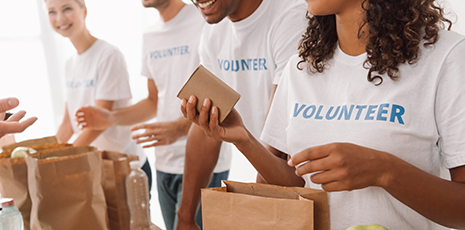 Volunteer holds canned item putting into brown paper bag.