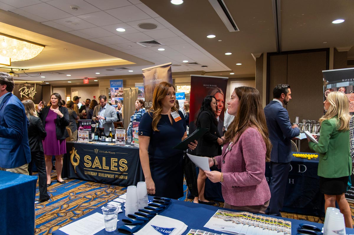 Girl in black blazer exchanging contact information with a company rep at career fair.