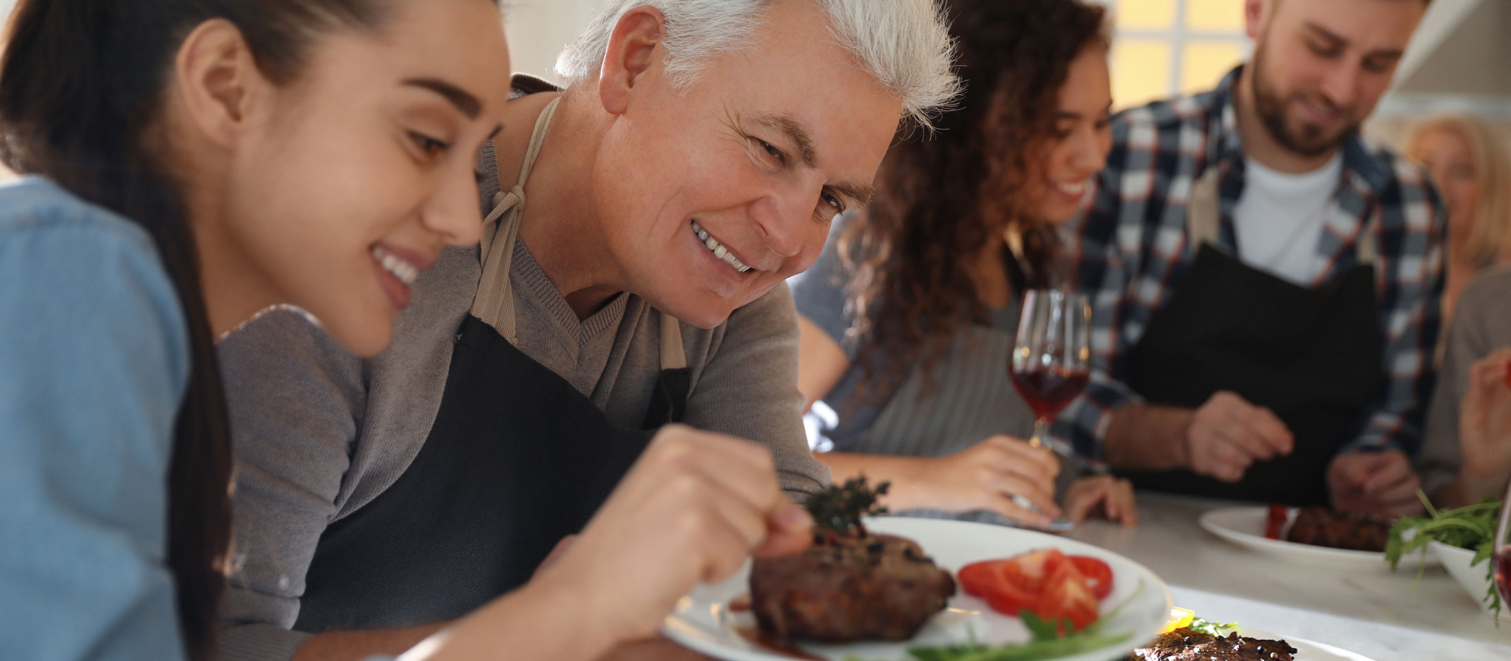 Photo of a young woman and older gentleman plating some food.