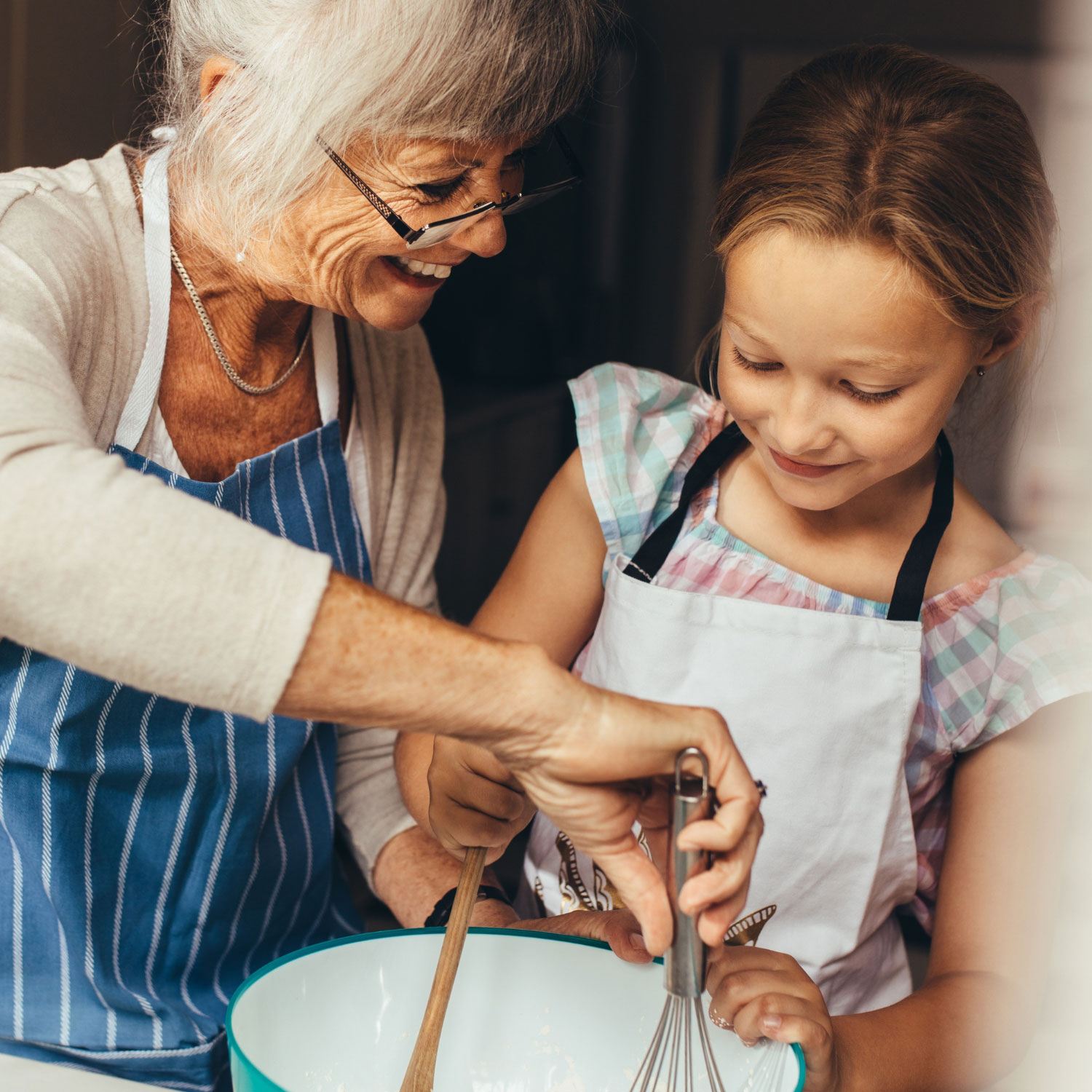 Photo of a grandma and grandaughter stirring ingredients in a bowl.