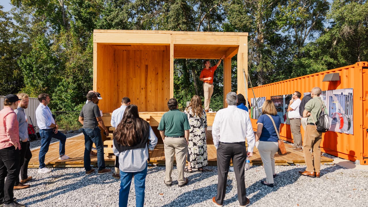man explaining a wood structure to an audience
