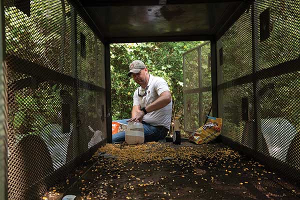 A man puts feed into a cage