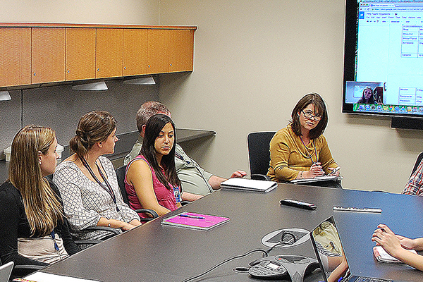 faculty member and students at conference table