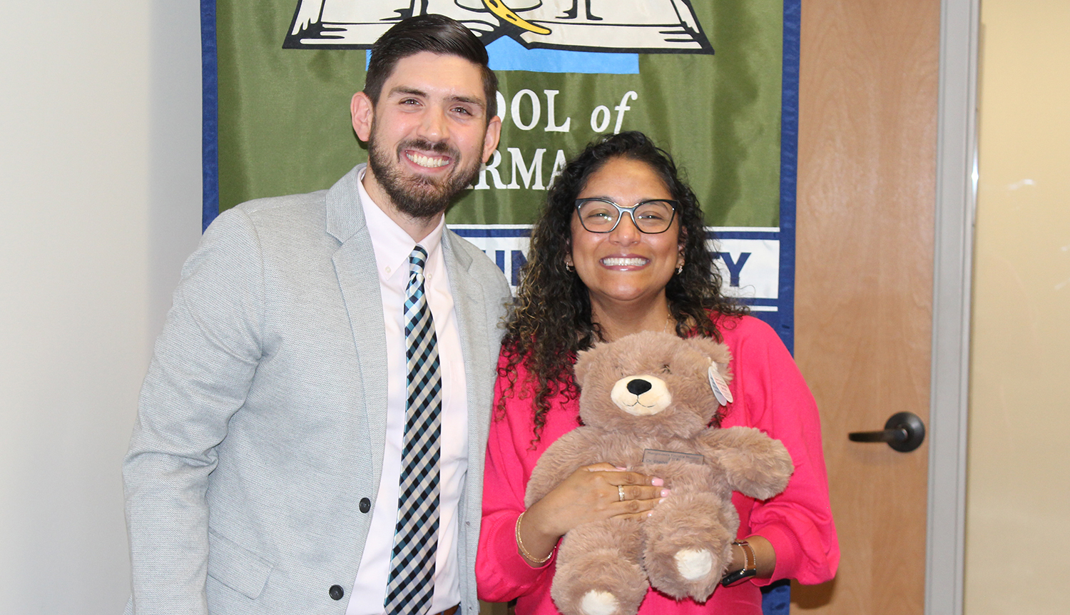 Two people stand holding a teddy bear