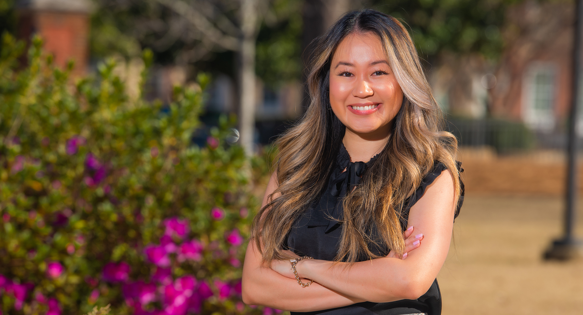 Linda Tran stands by flowering bush