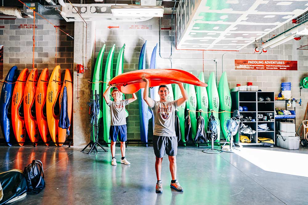 Two students carry at kayak