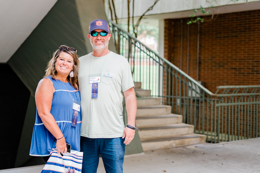a mom and dad posing in front of the Haley Center steps holding 