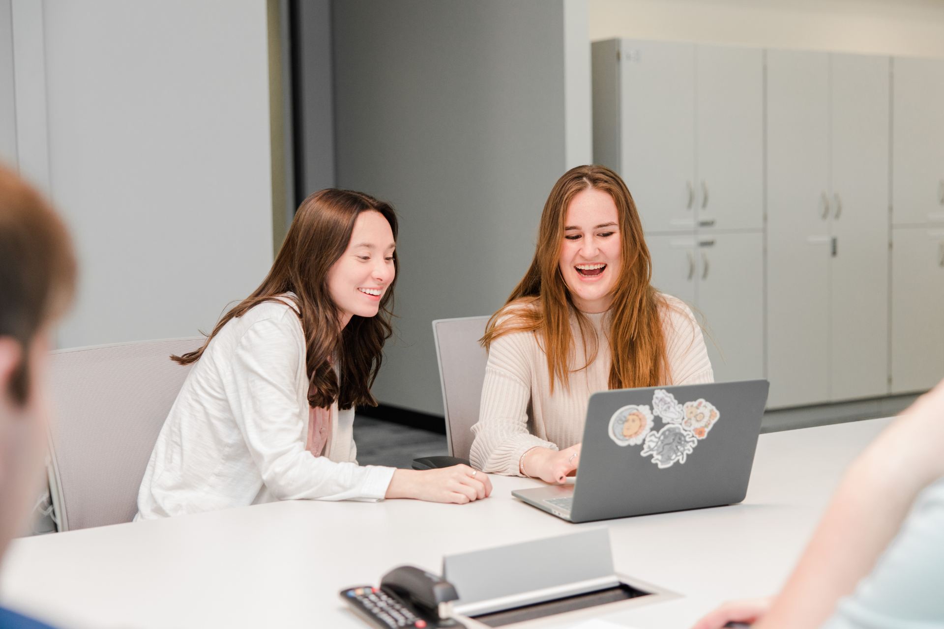 two happy students at a classroom table with laptop